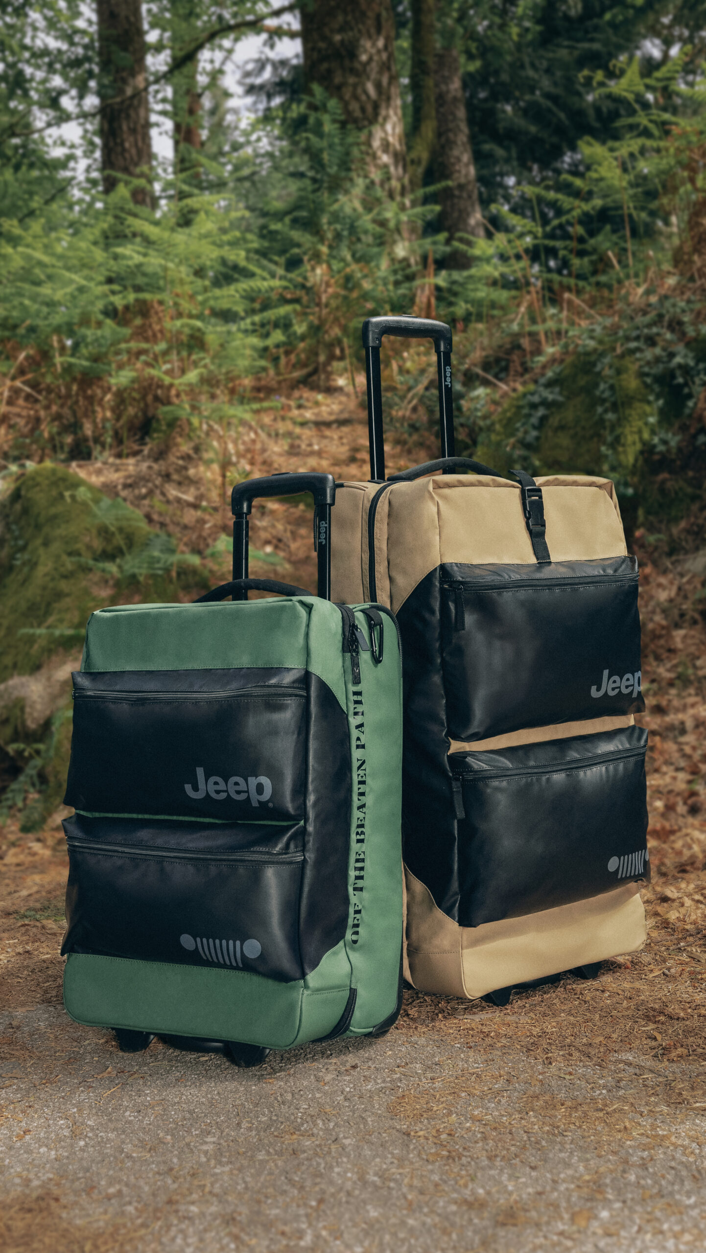 Een groen en een beigekleurige reistas van Jeep in het bos op een looppad met steentjes